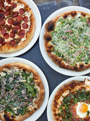 overhead view of four pizzas of various colors and toppings