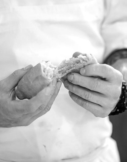 close-up of chef tearing piece of bread in-two