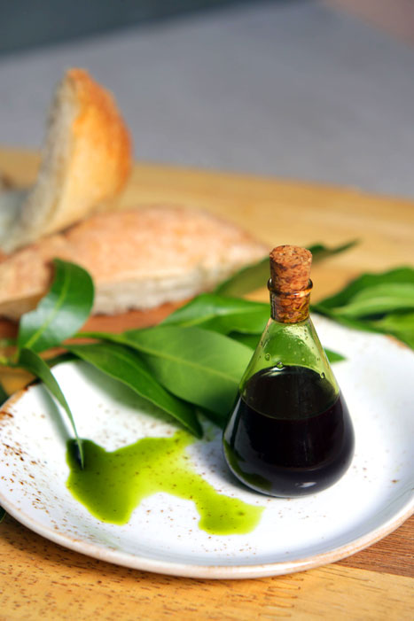 plate of oilve oil and bread styled with green leaves